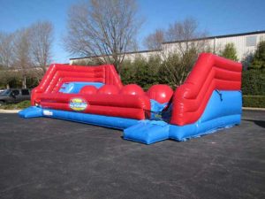 Picture of the Big Baller inflatable. Inflatable is mostly blue with red trim and four giant red inflatable balls lined up in the middle of the inflatable.