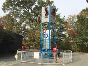 Picture of uniformed attendants supervising climbers on a mobile urban climbing wall.