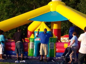 Picture of a uniformed attendant cheerfully supervising an toddler inflatable.