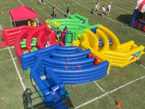 Overhead of the Dizzy X game. It is a large maze obstacle course with a spinning platform in the center. The inflatable is divided into four quadrants. The quadrants are red, green, yellow and blue.